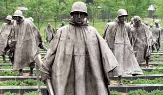 Korean War - The statues - Plodding in a V-formation, in wind-whipped ponchos, 19 men in full gear trek over a field of juniper. Graphite beams stretching horizontally between them act as obstacles. The ethnically diverse group represents those who fought the war on foot: 14 are Army troops, three are Marines, one a Navy corpsman and one an Air Force forward observer. The 19 are reflected in the wall to their right, doubling their number to 38 - a reference to the 38th parallel dividing North and South Korea.